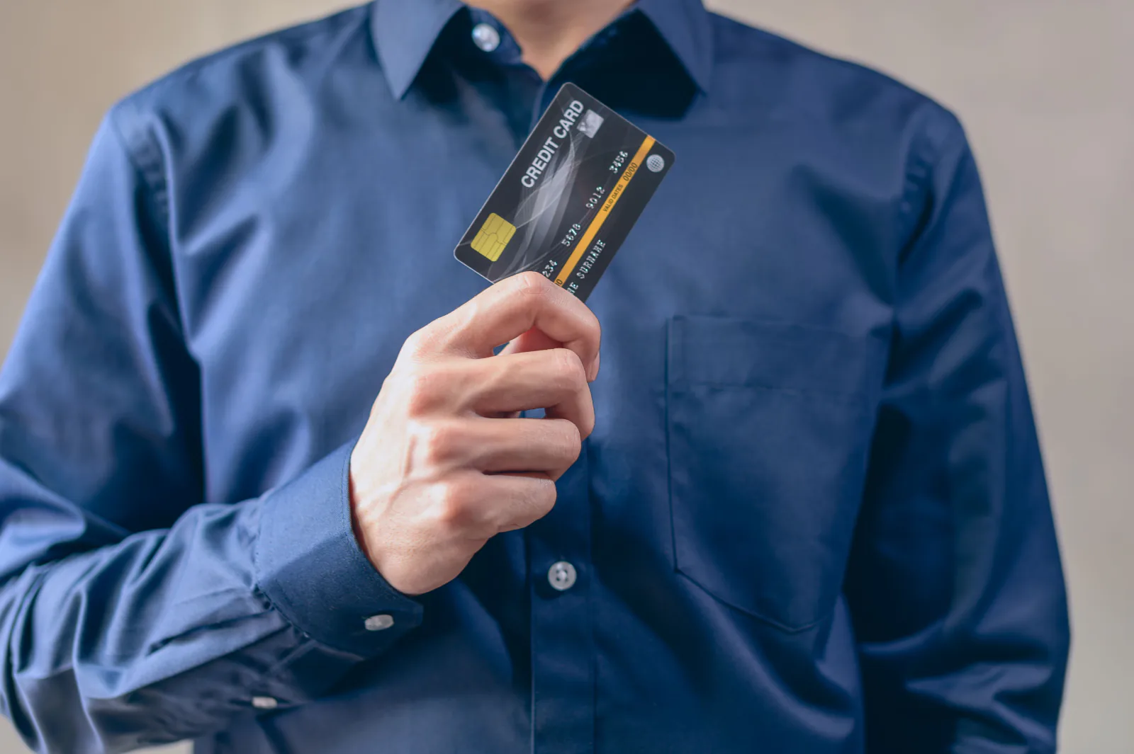 Hand holding a credit card in front of a shirt pocket, choosing a no-foreign-transaction-fee travel card