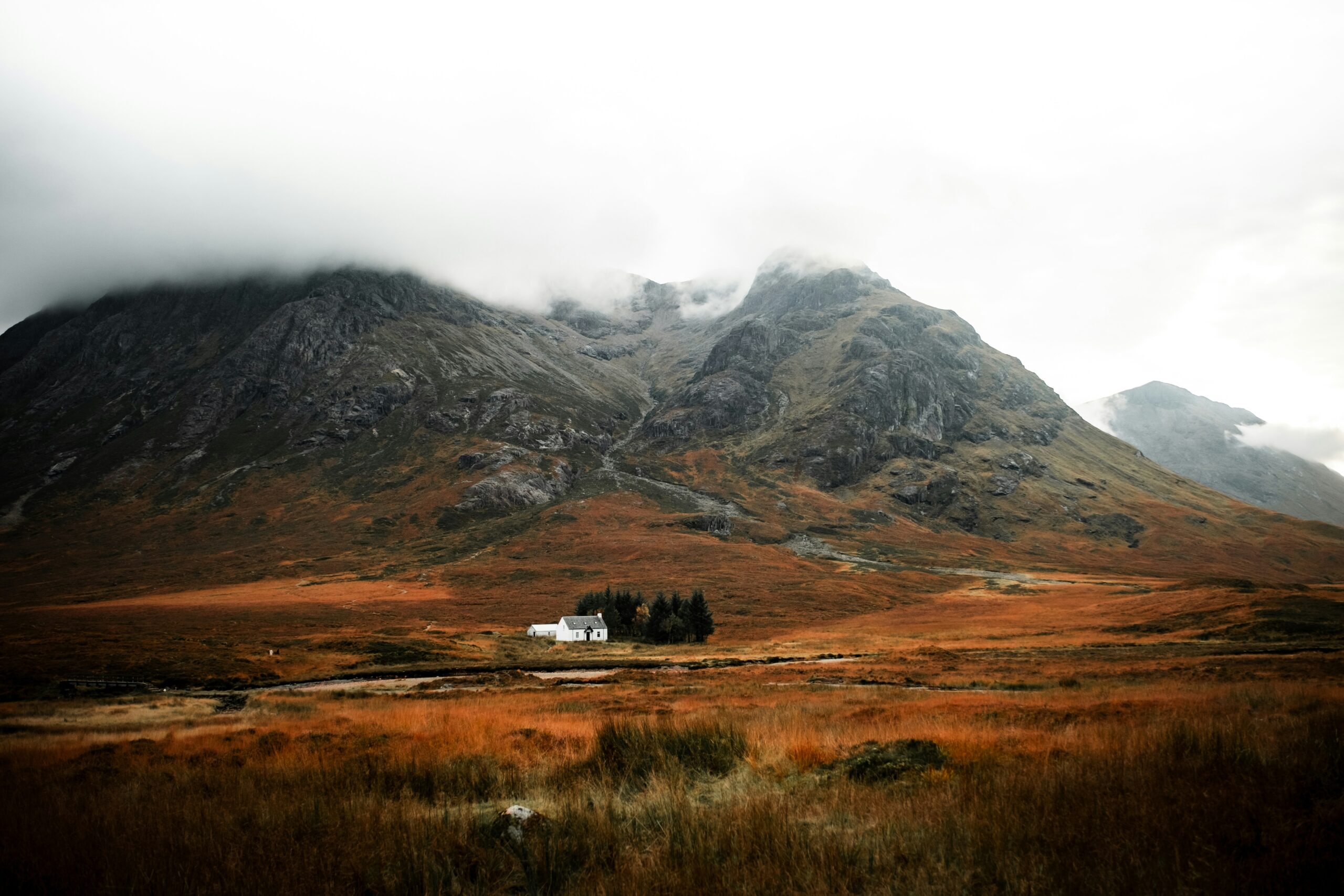 A small white house sits in a vast scottish landscape - moody Highland weather, wild camping in Scotland 2026