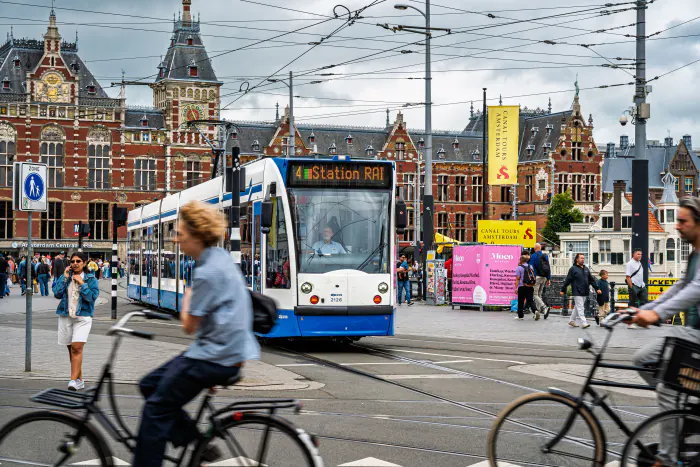 Amsterdam tram passing canal-side houses with bicycles parked along the street – getting around during ADE week