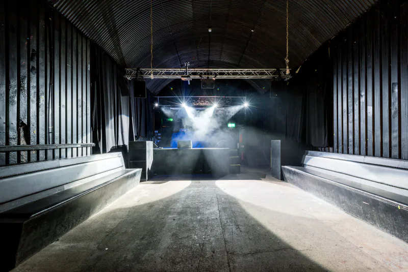 Empty warehouse-style club interior with stage lighting and smoke – inside an ADE festival venue