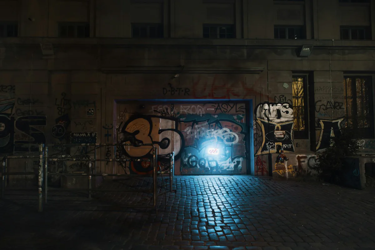Lit graffiti-covered club door on a cobbled street at night – how Berlin club door policies work