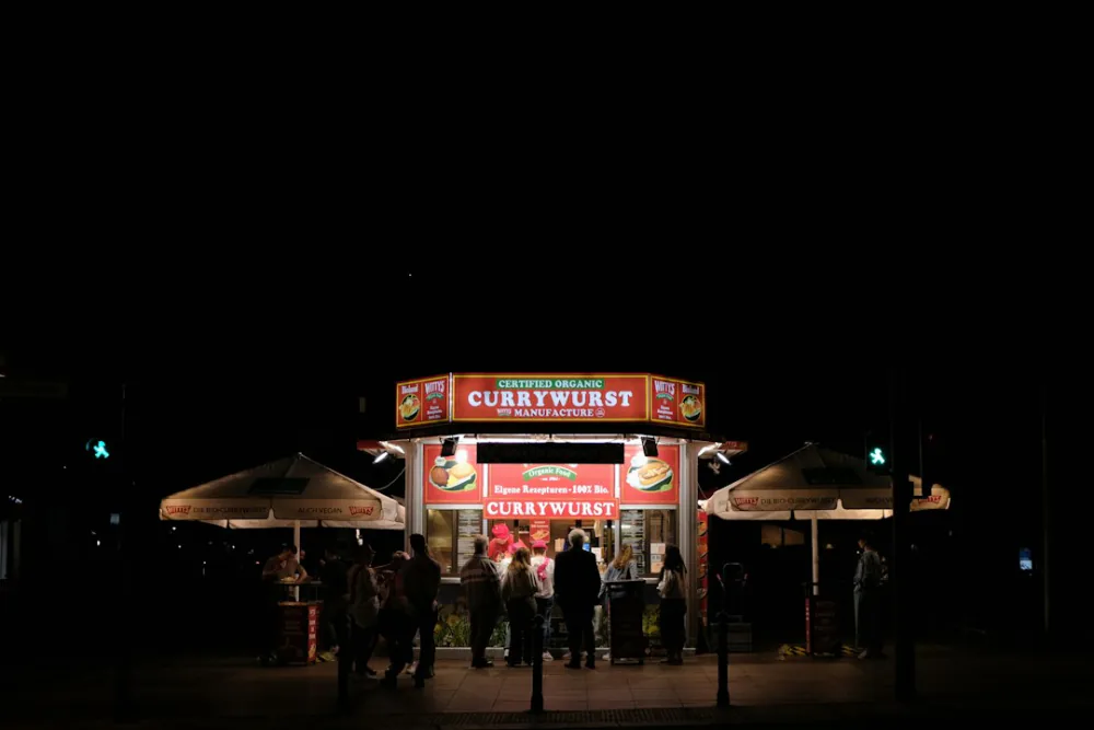 People queuing at a lit currywurst stand at night – queue behaviour before a Berlin club