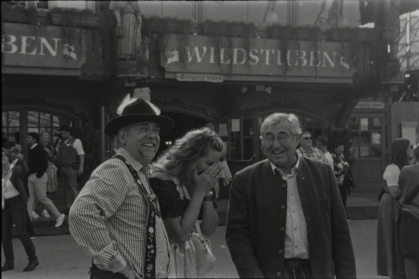 Friends in traditional Lederhosen and Dirndl outside a Munich beer tent entrance - what to wear and festival etiquette at Oktoberfest 2026
