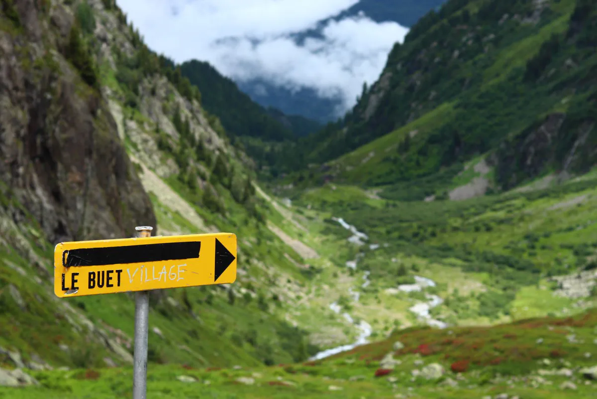 Yellow Le Buet trail signpost in a green alpine valley – getting to the TMB and staying safe, Vallorcine near Chamonix