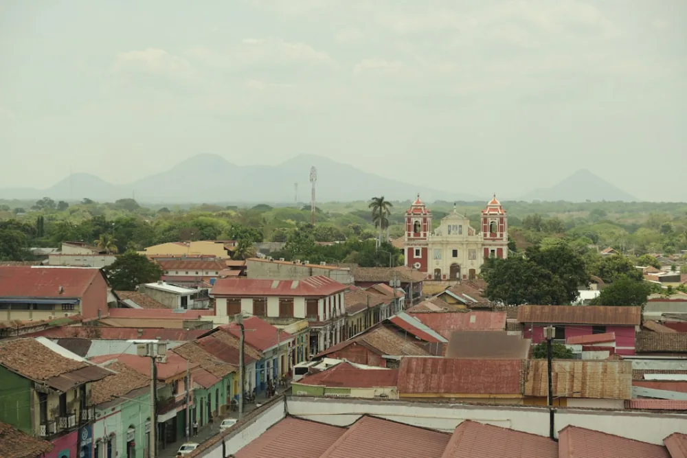 Leon's colonial rooftops and El Calvario church below the volcanic range – volcano boarding tour costs, Nicaragua