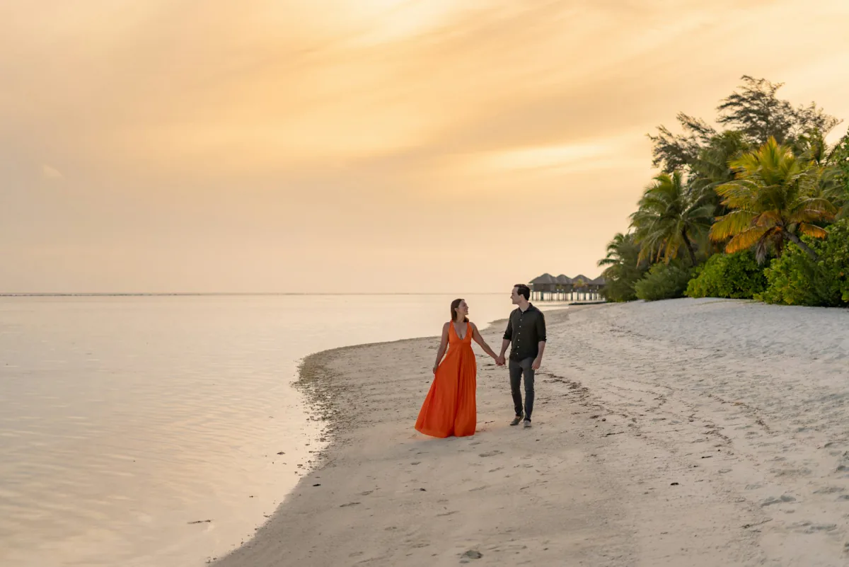 Couple walking a resort beach at sunset – mistakes first-timers make, Caribbean