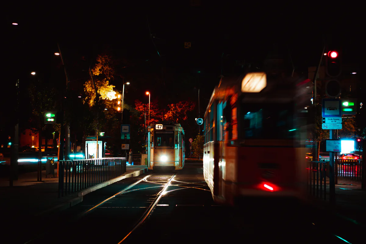 Night trams streaking along a lit Budapest street – How do you get there — and home at 5 a.m.?