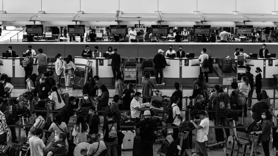 Passengers queuing at a busy airport check-in desk - comparing Ryanair and Wizz Air base fares in 2026