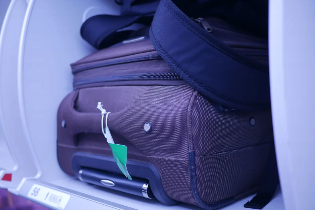 Cabin bag and small suitcase stowed in an aircraft overhead locker - what each airline lets you carry free