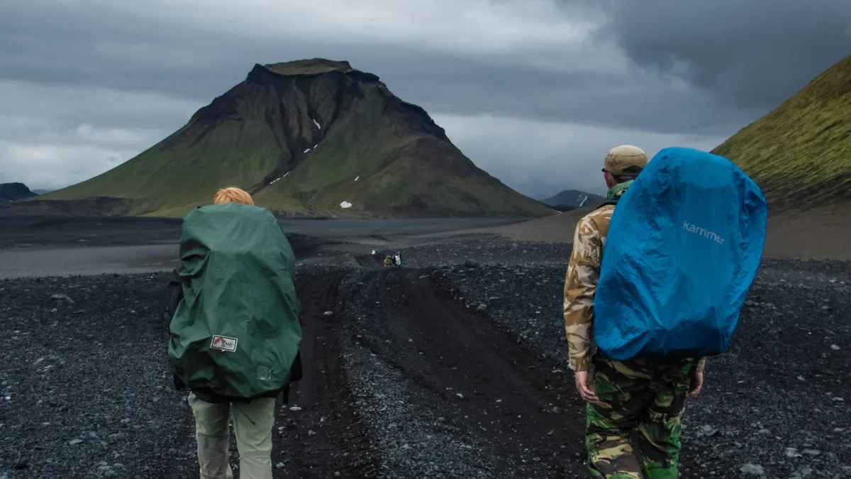 Two hikers walking a gravel track between highland slopes – Laugavegur trail daily stages, Iceland