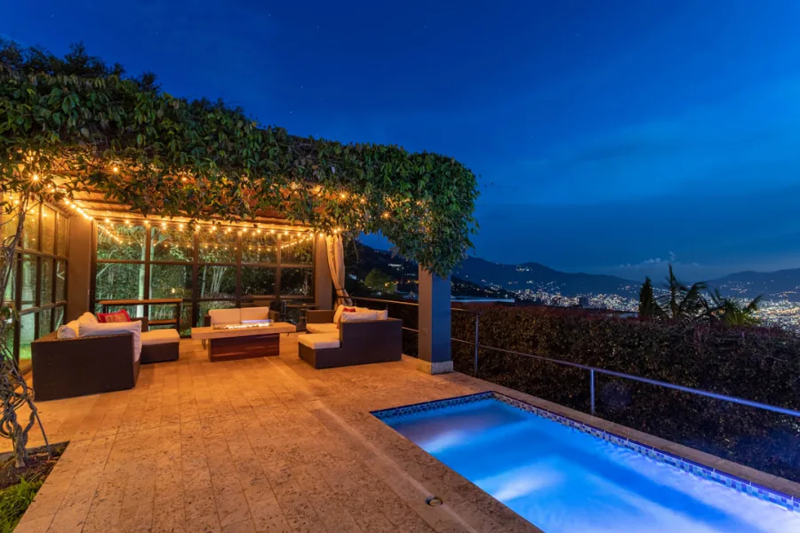 Rooftop lounge terrace with pool and seating overlooking the lit Medellin valley at night – What Are the Best Clubs and Bars in Medellin Right Now?