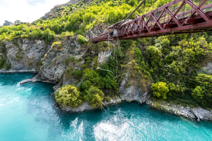 Bungee jumper falling towards a turquoise river gorge – the four adrenaline sports standard policies exclude