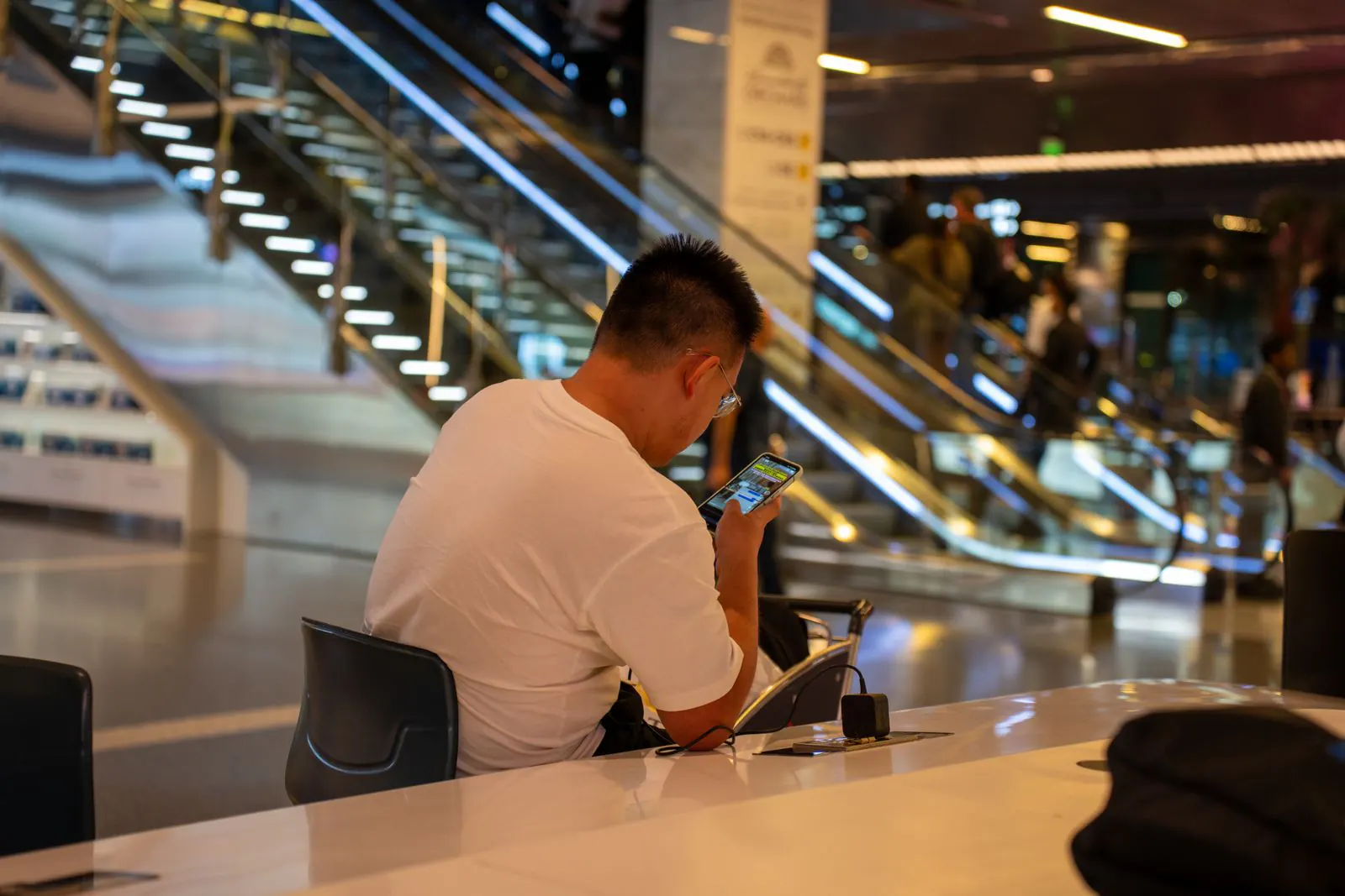 Stranded traveller checking rebooking options on a phone in an airport terminal – what to do in the first hour