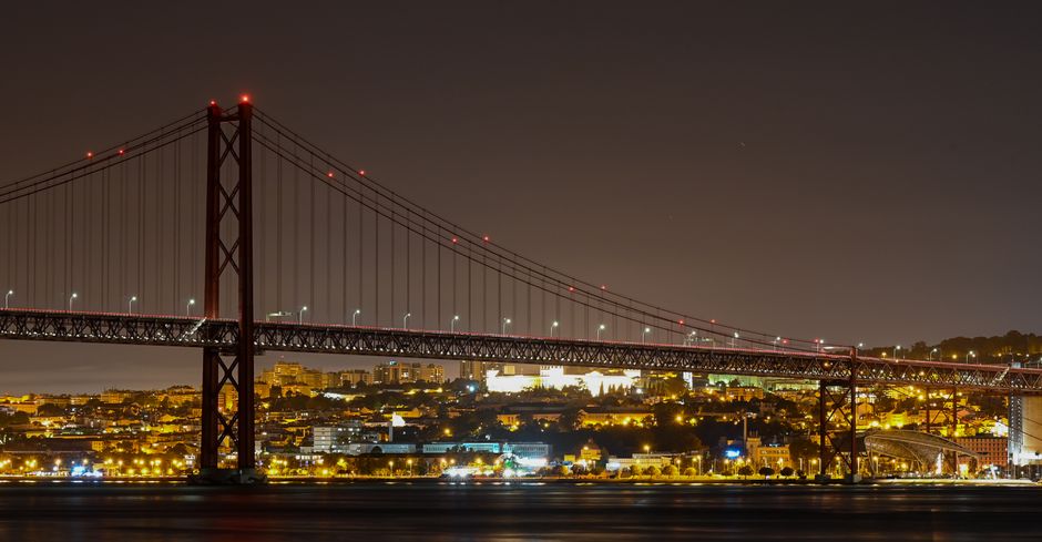 Capture of the illuminated 25 de Abril Bridge over the Tagus River in Lisbon at night. – Is Lisbon worth a night out in 2026?