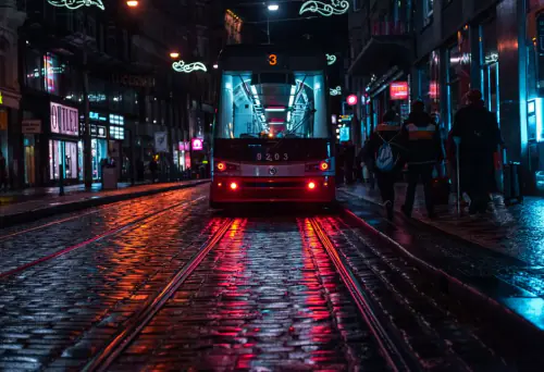 Tram on a cobblestone street in Prague, reflecting city lights on a rainy evening. – How Do You Get Around Prague at Night and Stay Safe?