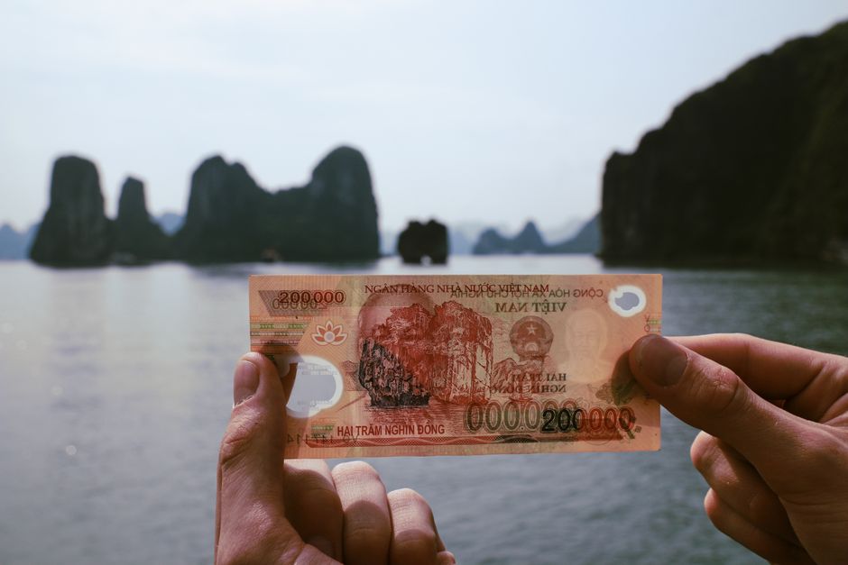 Hands holding Vietnamese Dong with Halong Bay in the background, a fusion of finance and travel. – Your Next Step: Build Your Own Daily Budget