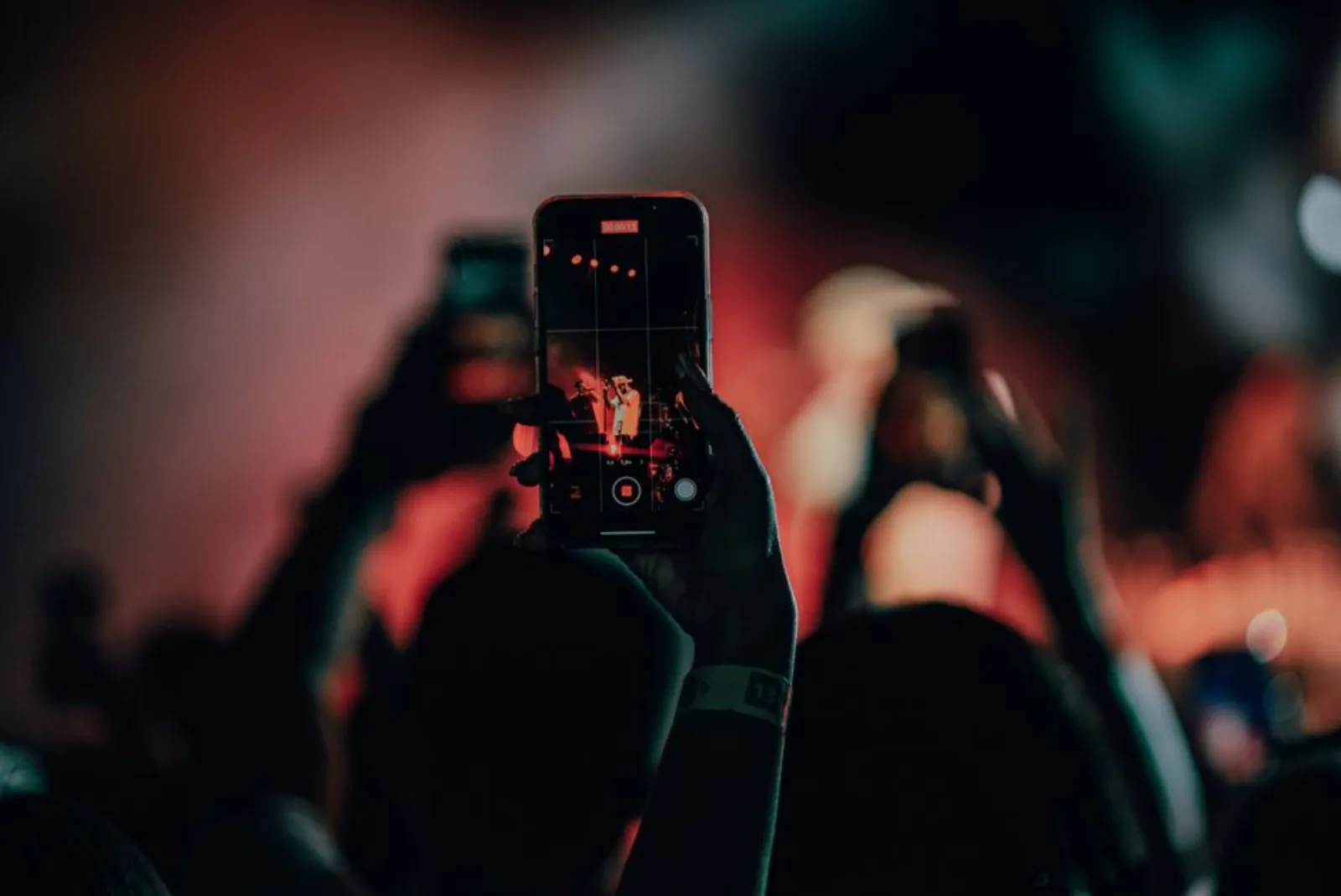 A close-up of a smartphone recording a lively concert scene with colorful stage lights. – Is Theft Covered at Festivals? Phones, Bags and Wristbands
